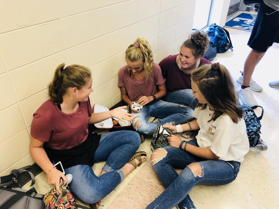 Students, Kathryn Moore, Avery Burleson, Jillian Francis, and Maddie Larkin laugh and talk while eating their lunch in the halls.